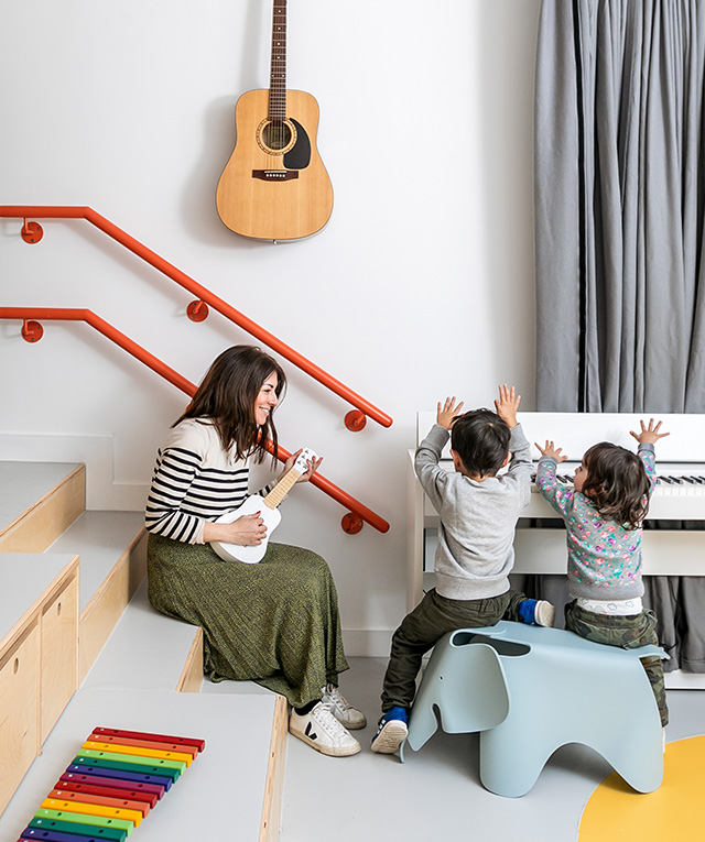 A woman playing guitar for children