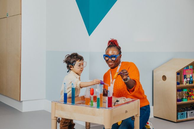 An educator and two children playing with a science kit