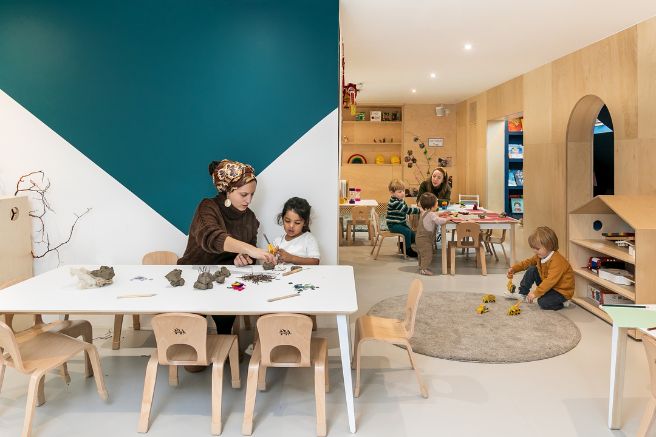 An educator and child doing crafts in a nursery playroom
