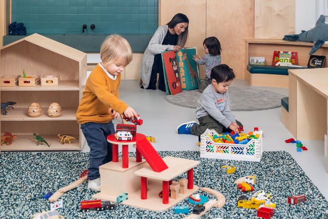 Children playing in a nursery playroom with an educator supervising them