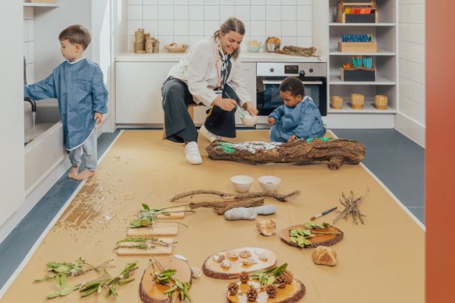An educator and children doing messy play in a nursery playroom