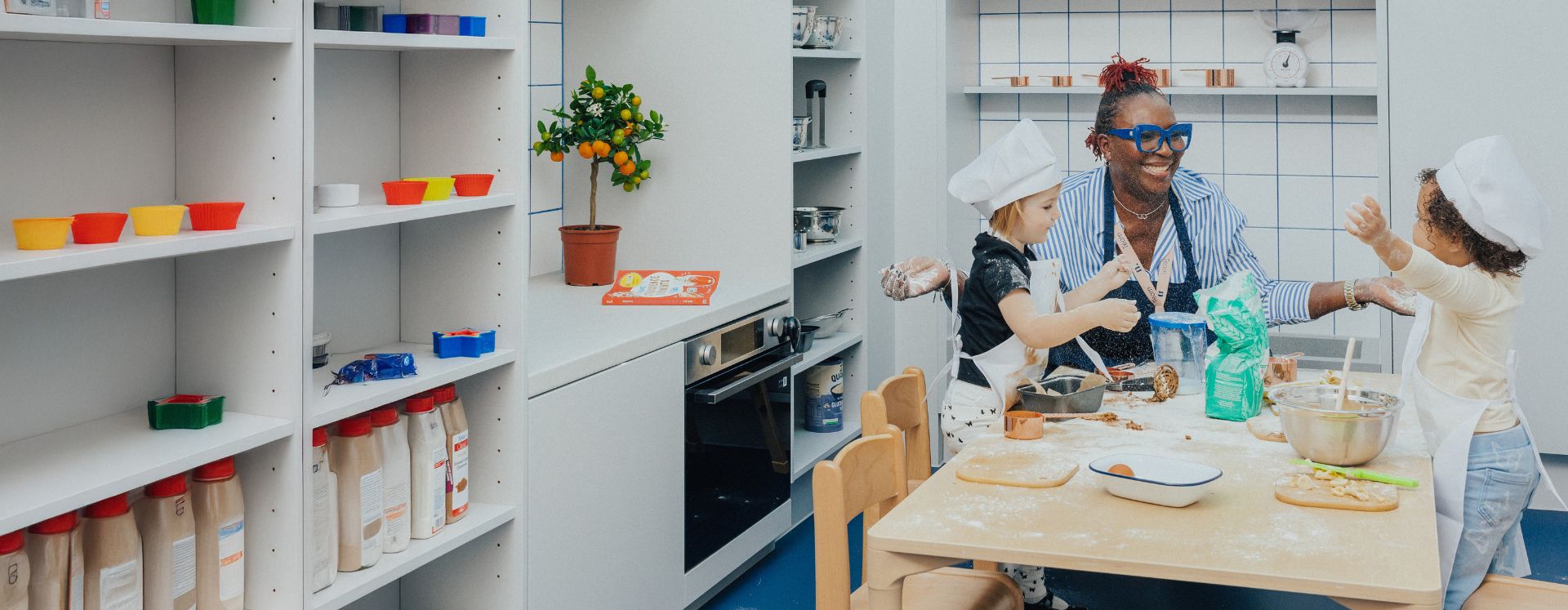 A nursery teacher and two children baking in the atelier