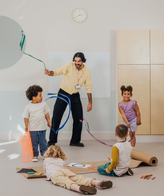 An educator and three children in a nursery doing a doodle dance
