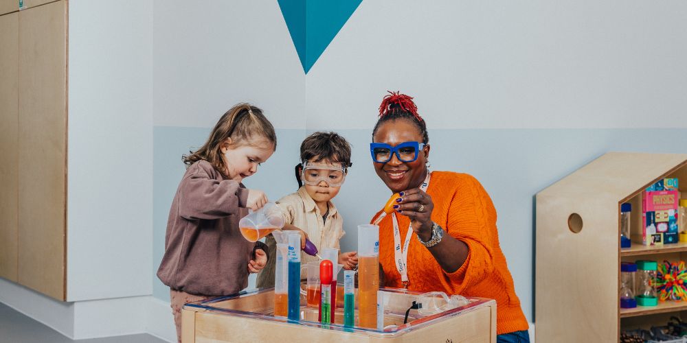 An educator and two children playing with a science kit