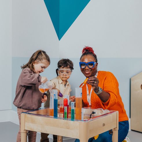 An educator and two children playing with a science kit