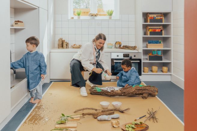 An educator and children doing messy play in a nursery playroom