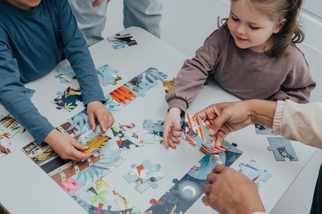 Children assembling a puzzle in the nusery playroom
