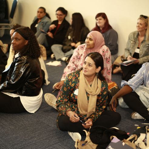 A group of women sitting on the floor at a conference