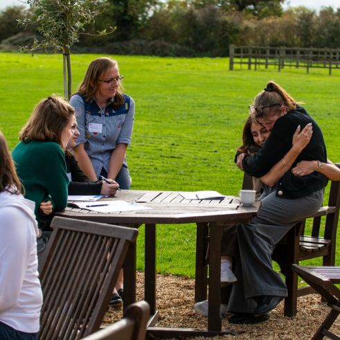 Two teammates hugging while the others look on and smile